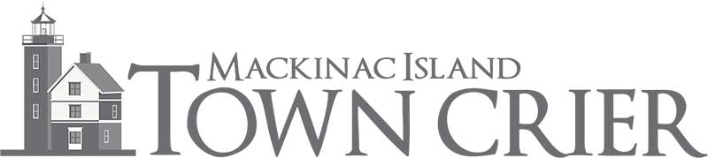 Logo for Mackinac Island Town Crier with a lighthouse and house graphic to the left of the publication name in bold, uppercase letters, representing a Premier Media Network offering Digital & Advertising Solutions.