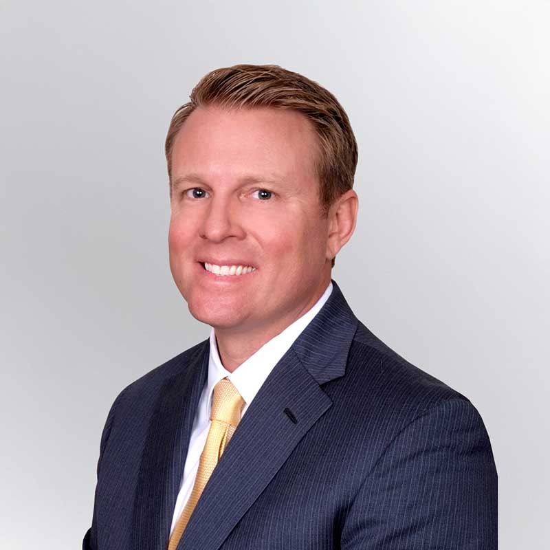 A man in a dark business suit and yellow tie poses for a professional headshot against a plain, light gray background—ideal for Premier Media Network or Video & Streaming professionals.